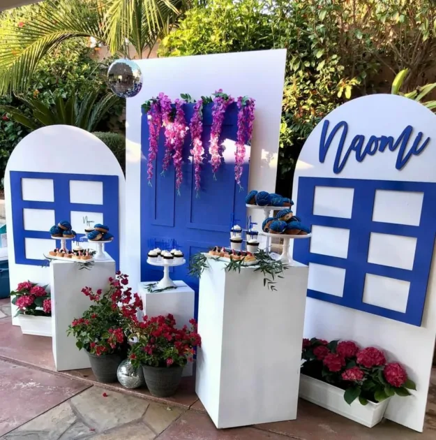 Mamma Mia Birthday Party White Pedestals With Dessert On Top With Windows Design On White Backdrop